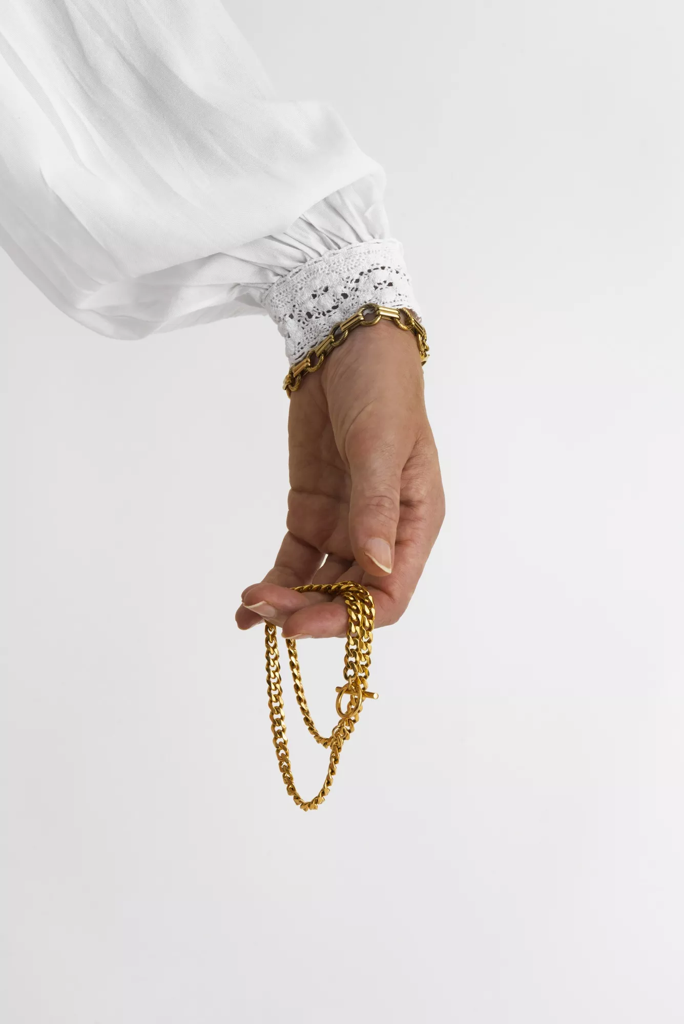 side view hand holding gold chains